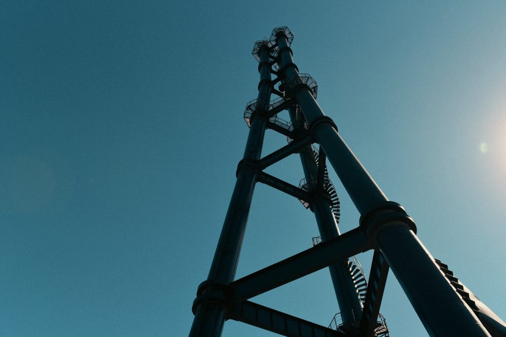 Estructura industrial de acero vista en contrapicado, con escaleras de caracol y plataformas contra el cielo azul.